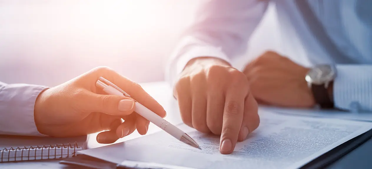 manos en una oficina con papeles y un bolígrafo